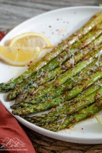 Roasted asparagus on a white plate with lemon