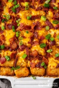 Close up of a Cowboy Tater Tot Casserole in a white baking dish.